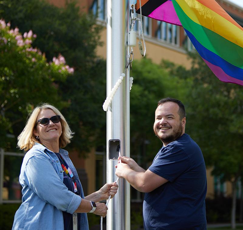 Two 博彩平台网址大全 employees raise the Pride flag at the company's San Rafael campus.